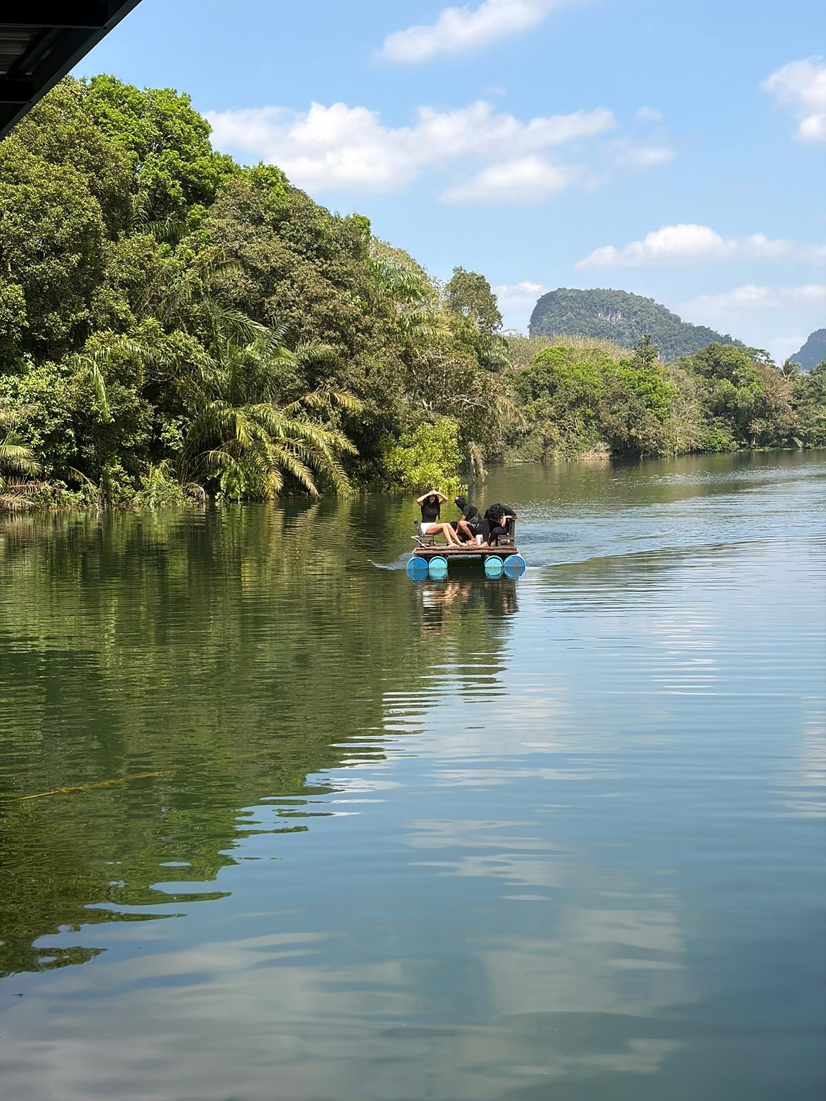 A raft drifting on a calm, jungle-lined waterway in the Krabi countryside