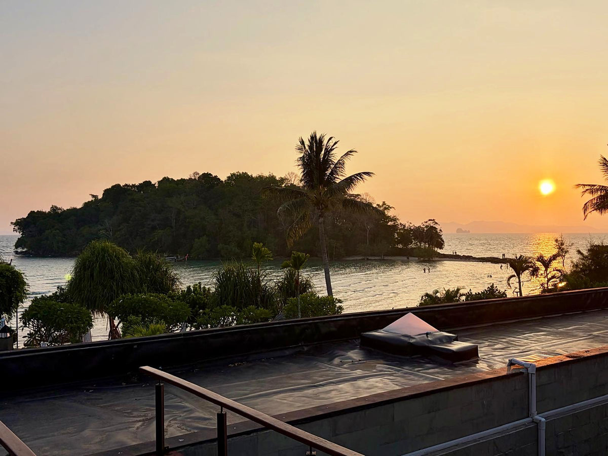 Sunset over a wooded islet and the bay, seen from a terrace on the Krabi coast