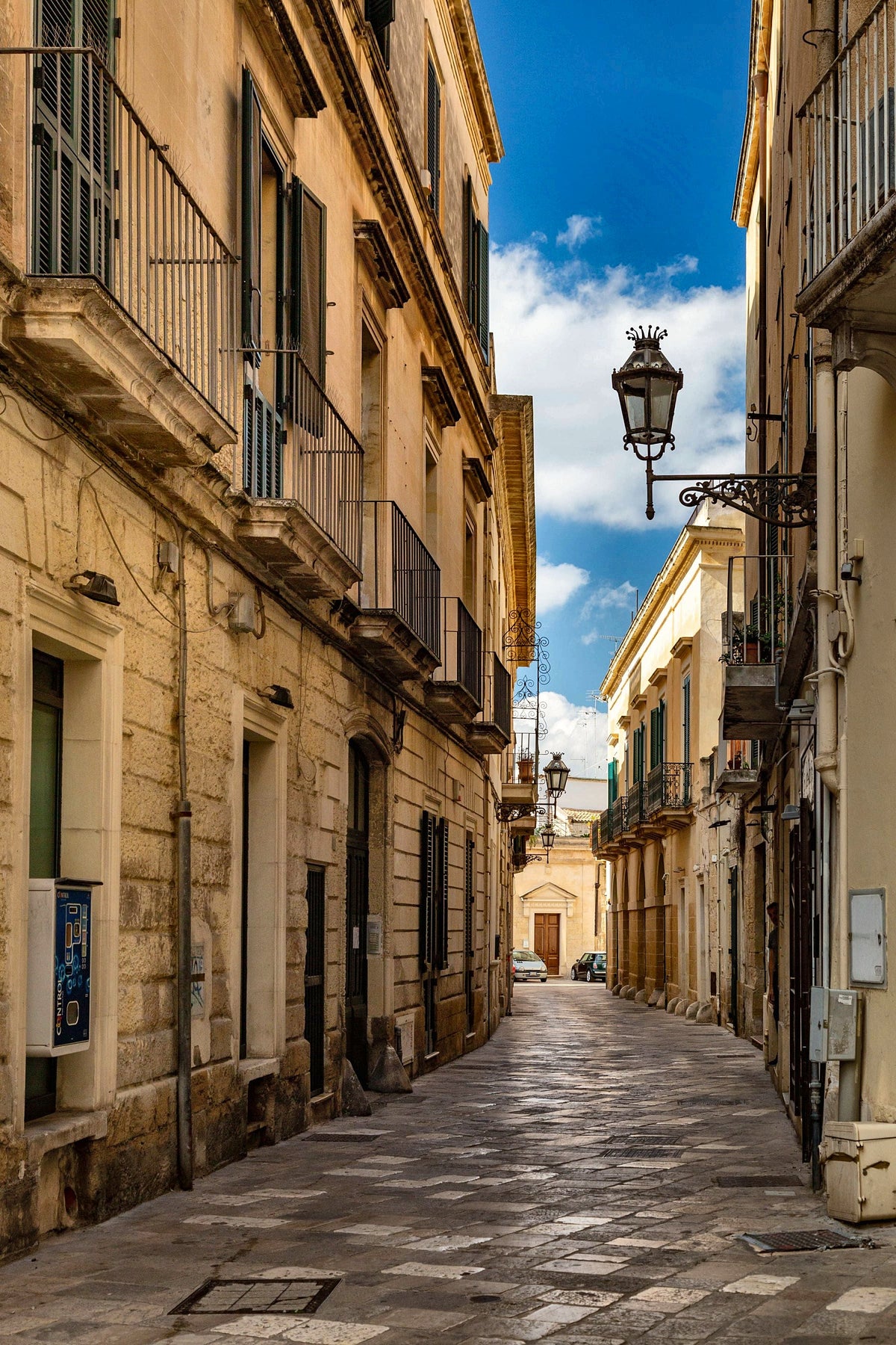 A cobbled street of balconies and lamps in historic Bari