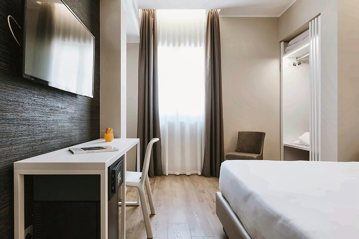 Deluxe room at Boston Hotel Bari with a desk and tall curtained window