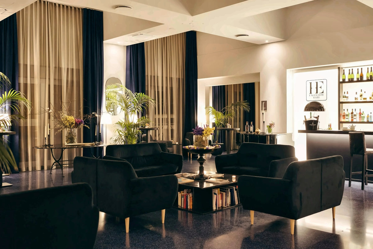 The lounge bar of Hotel Excelsior Bari with velvet armchairs and tall curtains