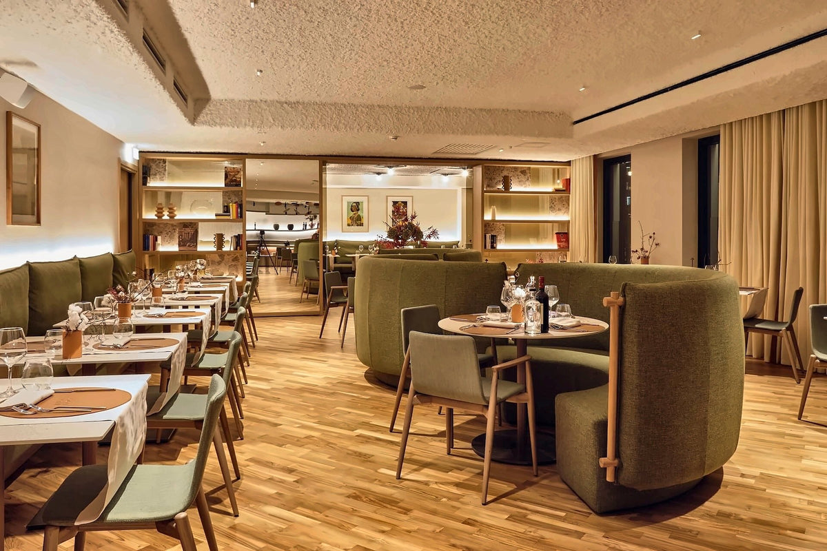 The restaurant at Il Leon d'Oro, with green velvet booths and set tables