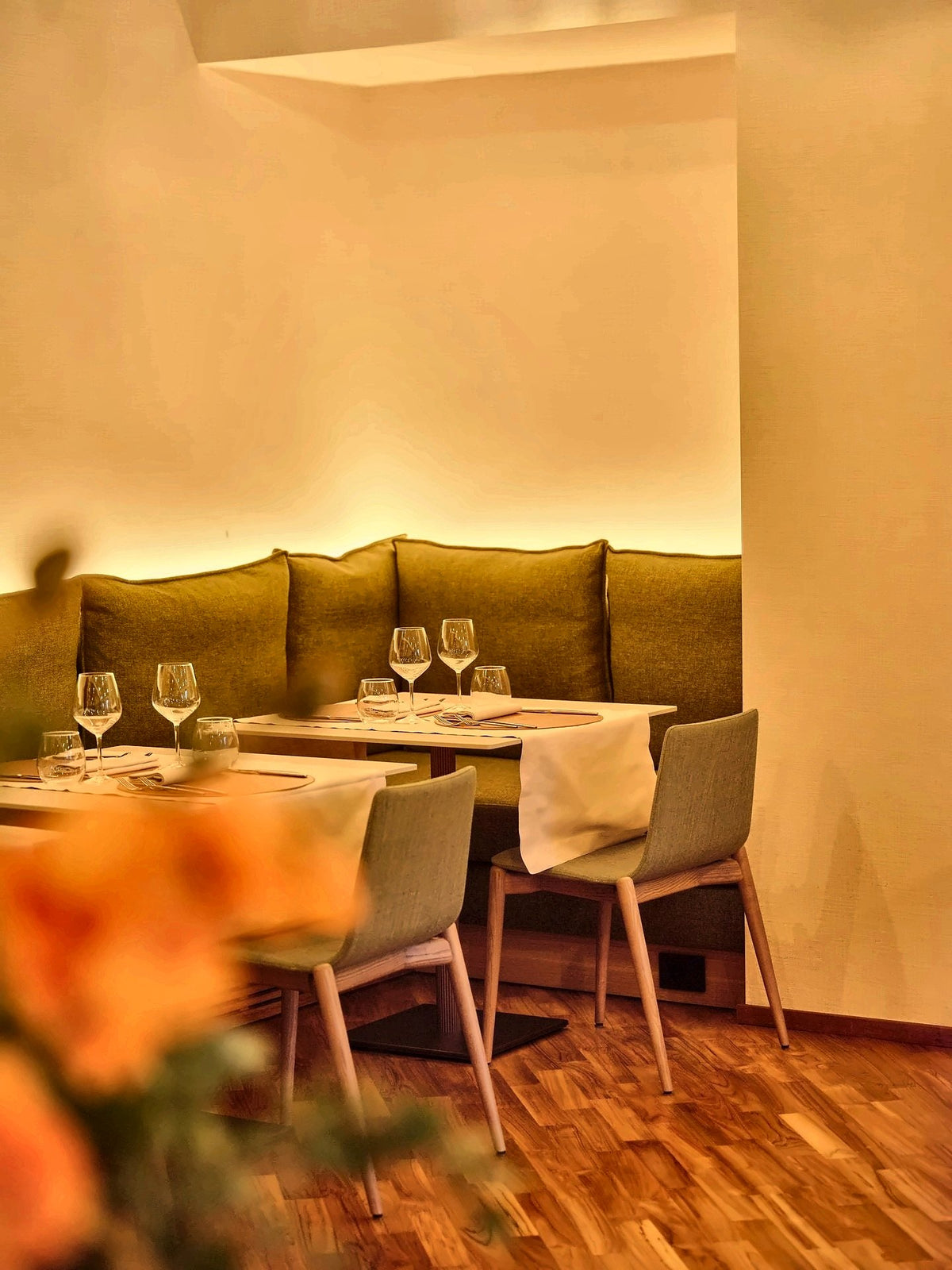 A warmly lit dining corner with a green banquette at Il Leon d'Oro