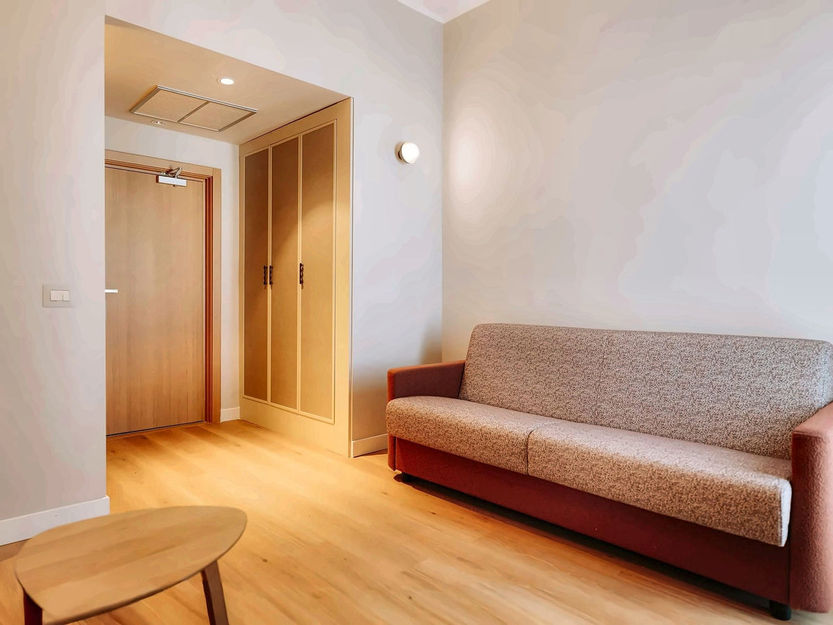 Junior suite sitting area at Mövenpick Hotel Bari with a sofa and oak floor
