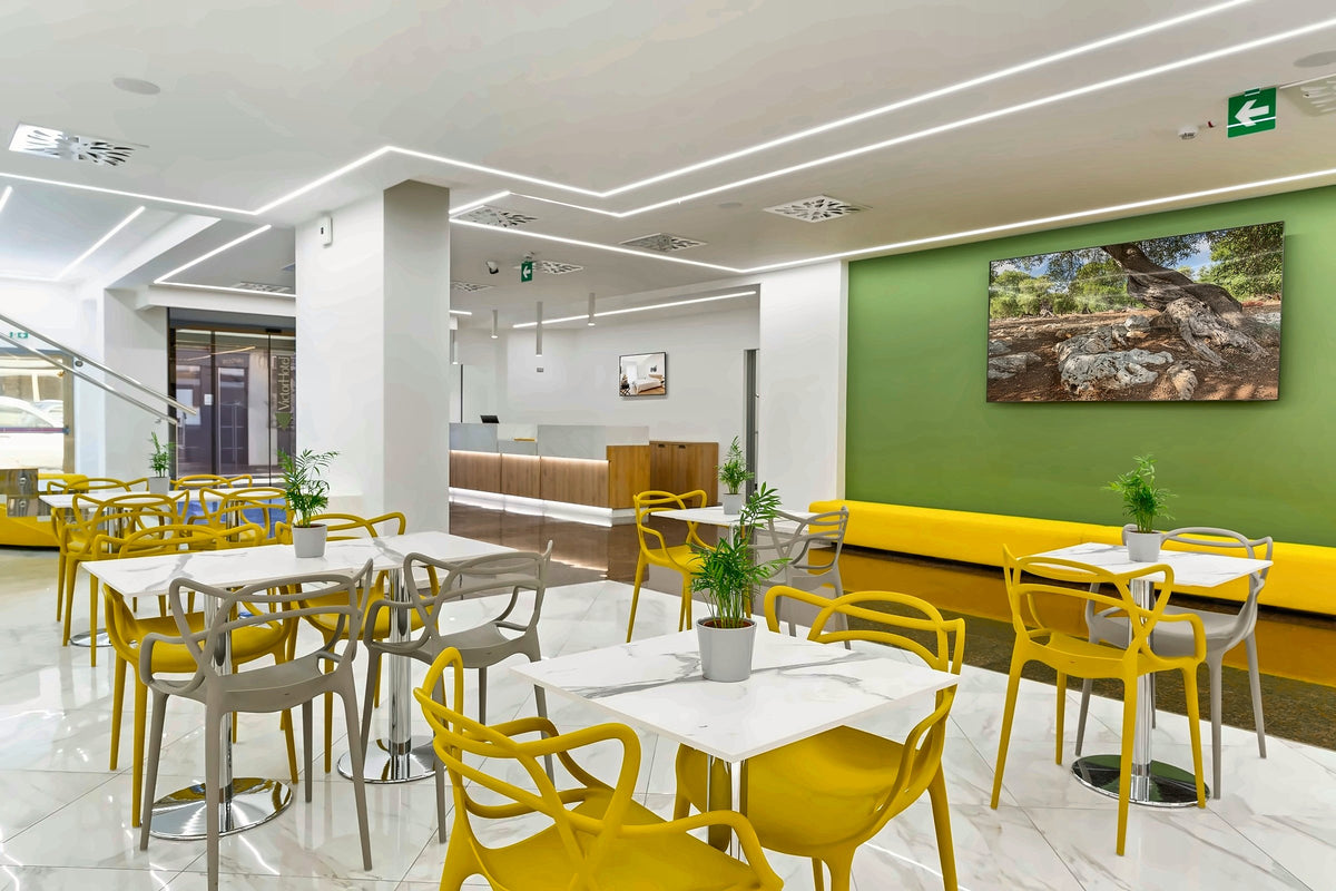 The bright breakfast room at Victor Hotel Bari with yellow chairs