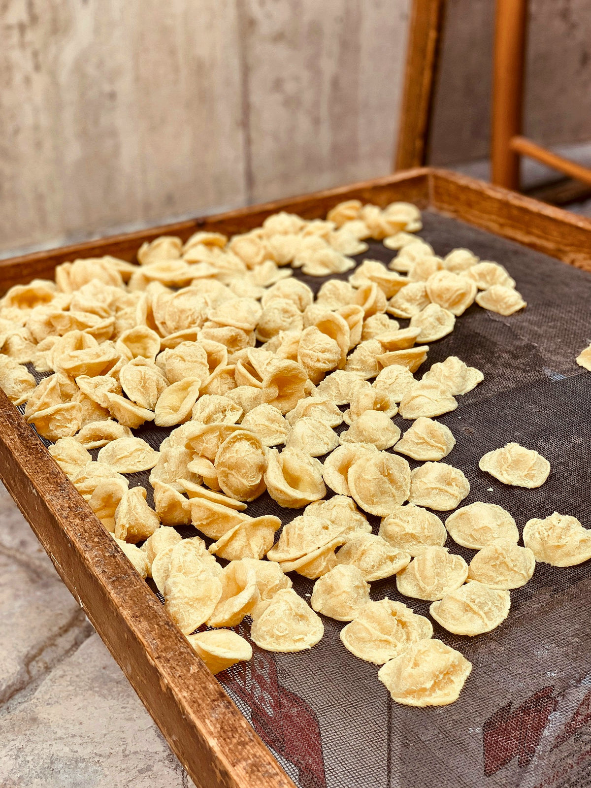 Fresh orecchiette drying on a wooden mesh tray