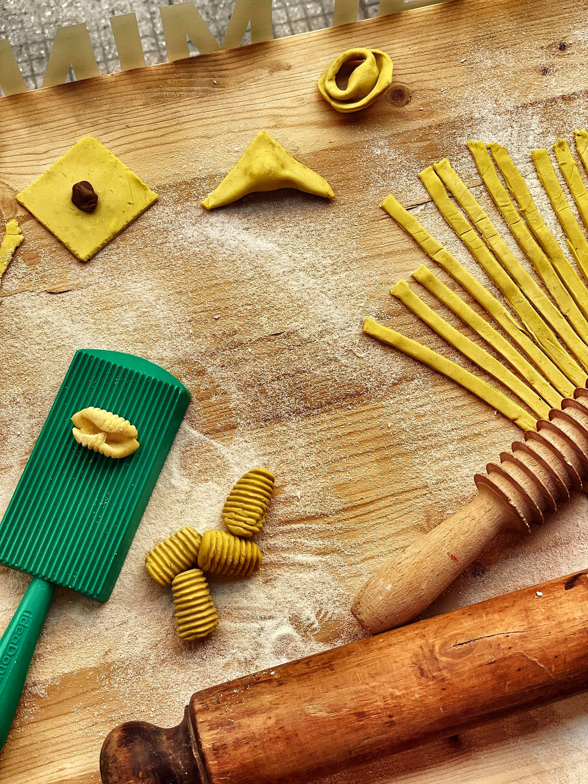 Hand-cut pasta shapes, a rolling pin and a gnocchi board