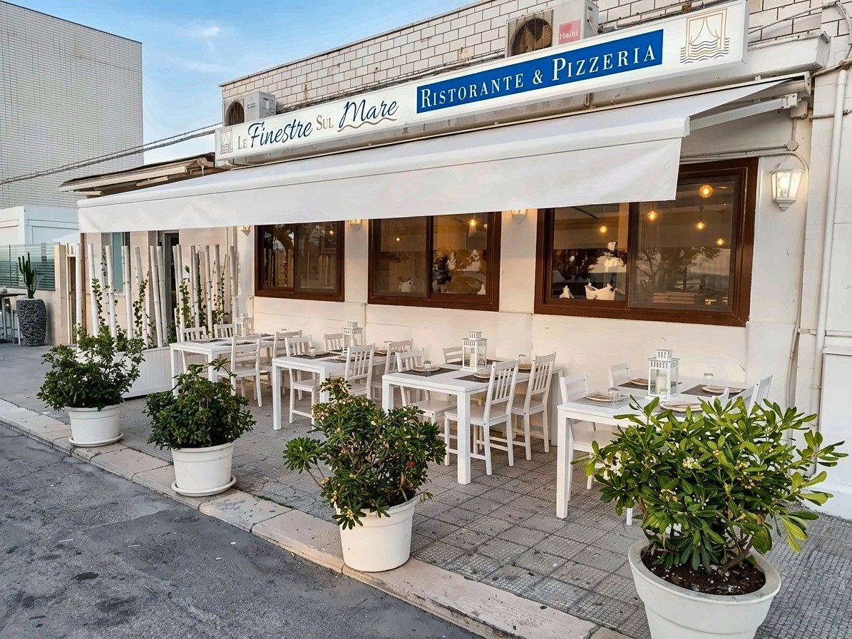 The terrace of Le Finestre sul Mare, set with white tables and potted plants