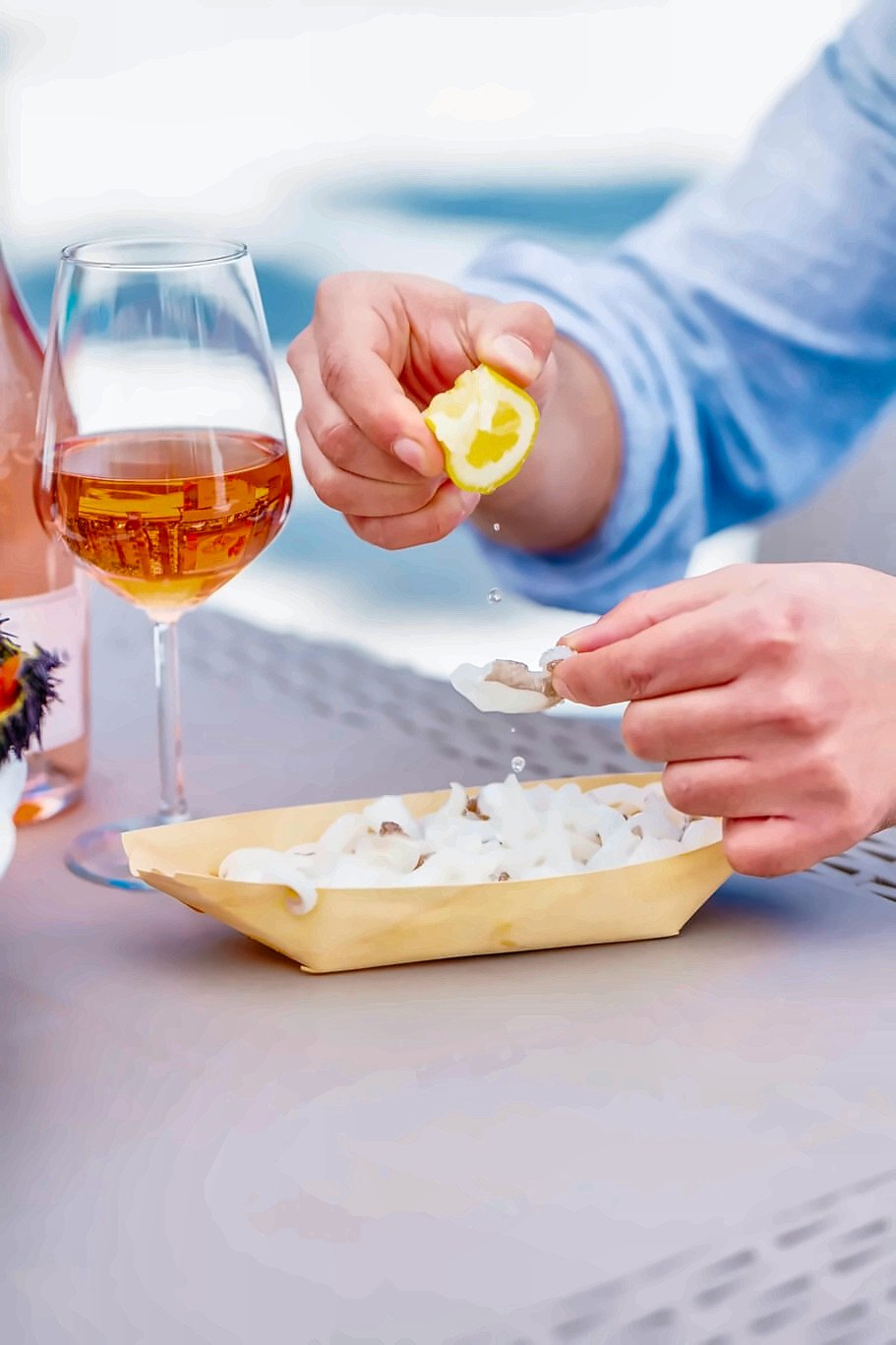 Lemon squeezed over a seafood starter with a glass of orange wine at Nicolaus Bistrot dal Mare