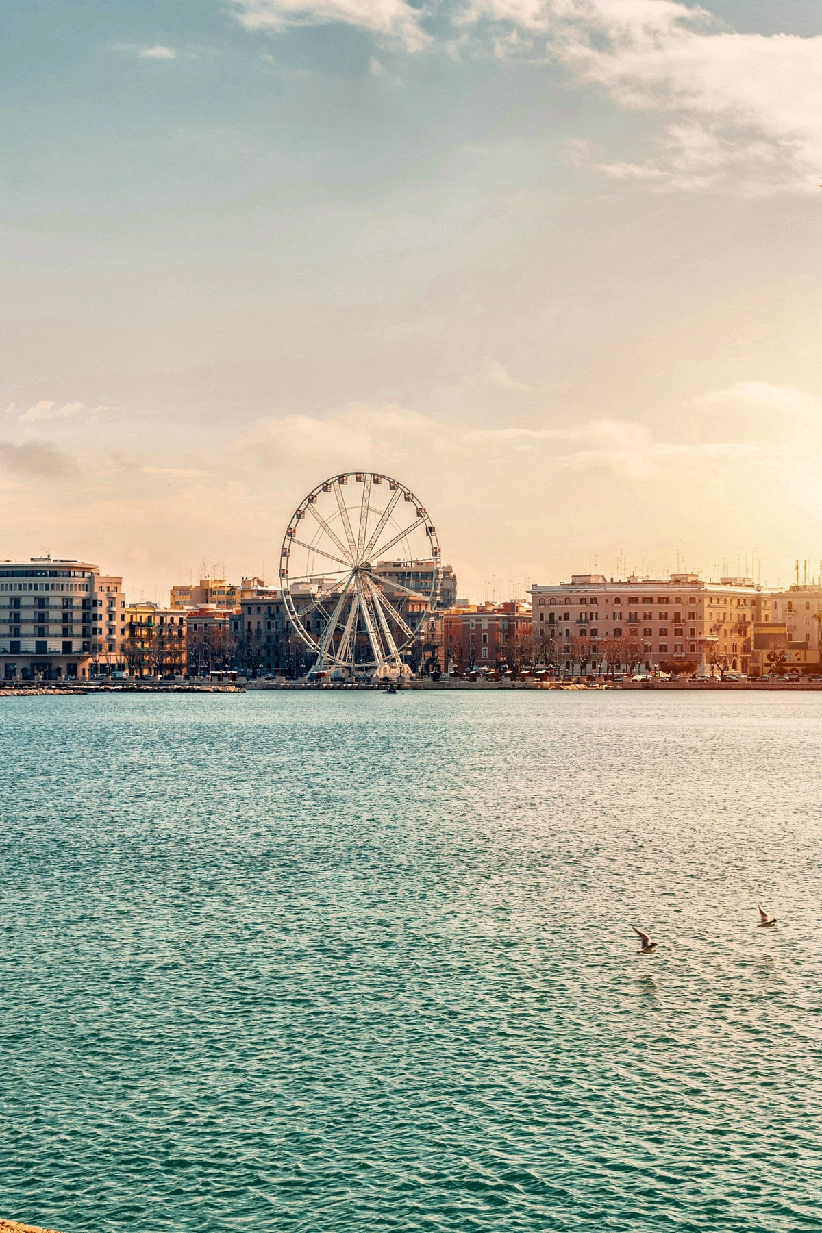 A Ferris wheel on the seafront, glowing at sunset