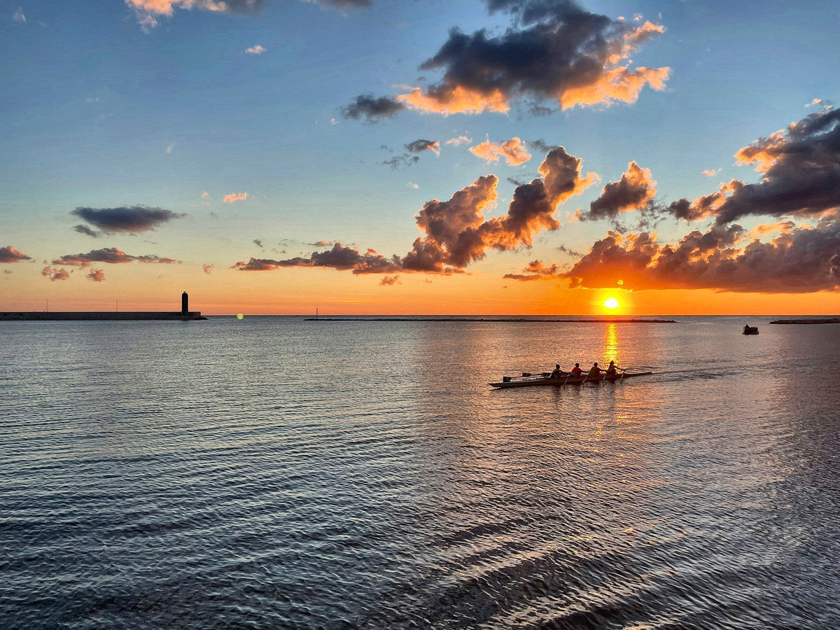 Rowers crossing the bay at sunrise off the Bari seafront