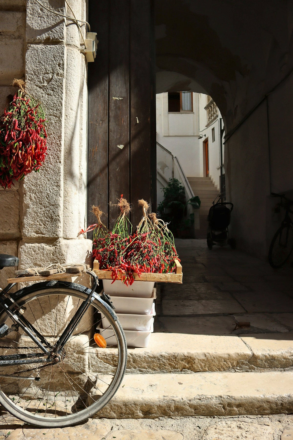 Strings of red peppers and a bicycle at a doorway in the old town