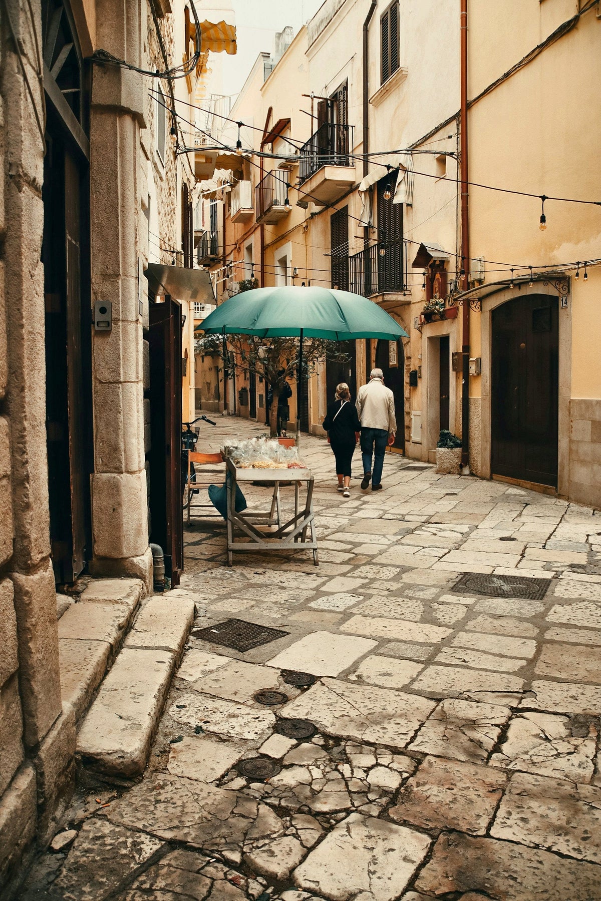A stroll under a green umbrella on the worn paving stones of Bari Vecchia