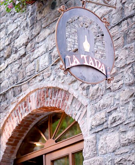 Stone archway and sign of La Tana