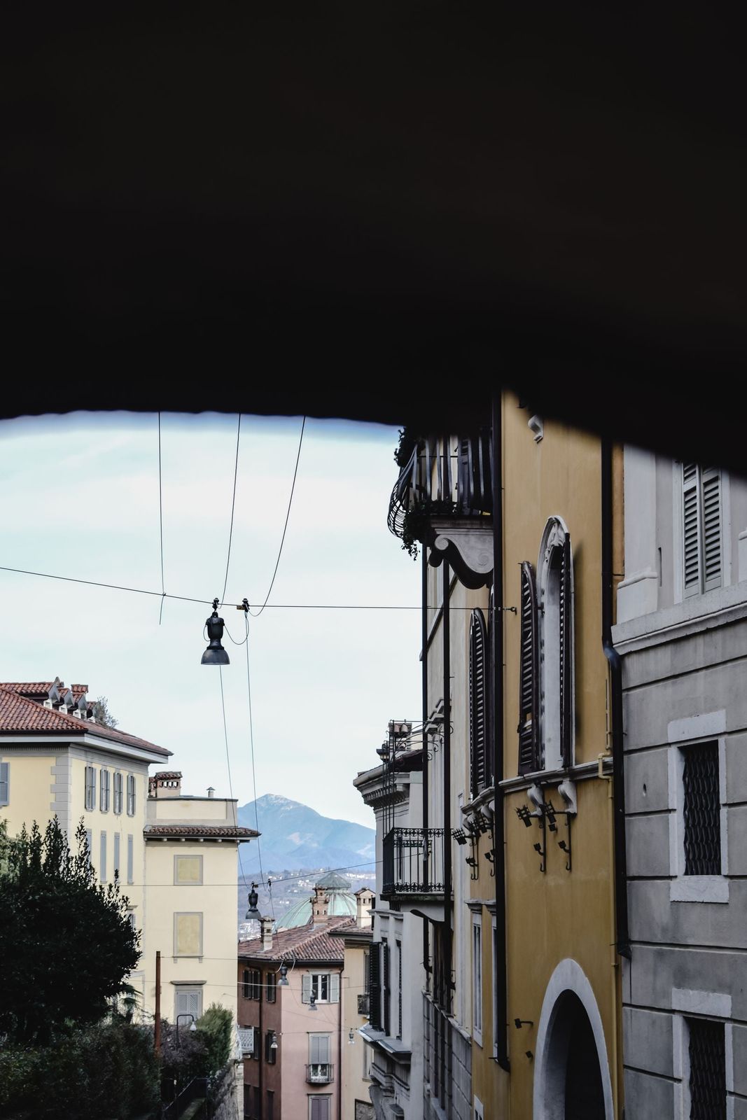 A quiet street in Bergamo with mountains beyond