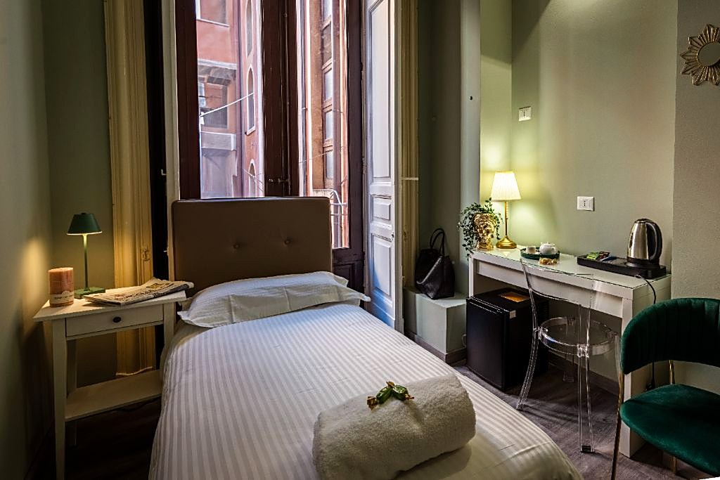 Single-bed room with a balcony window onto the street at Etnea Boutique Hotel