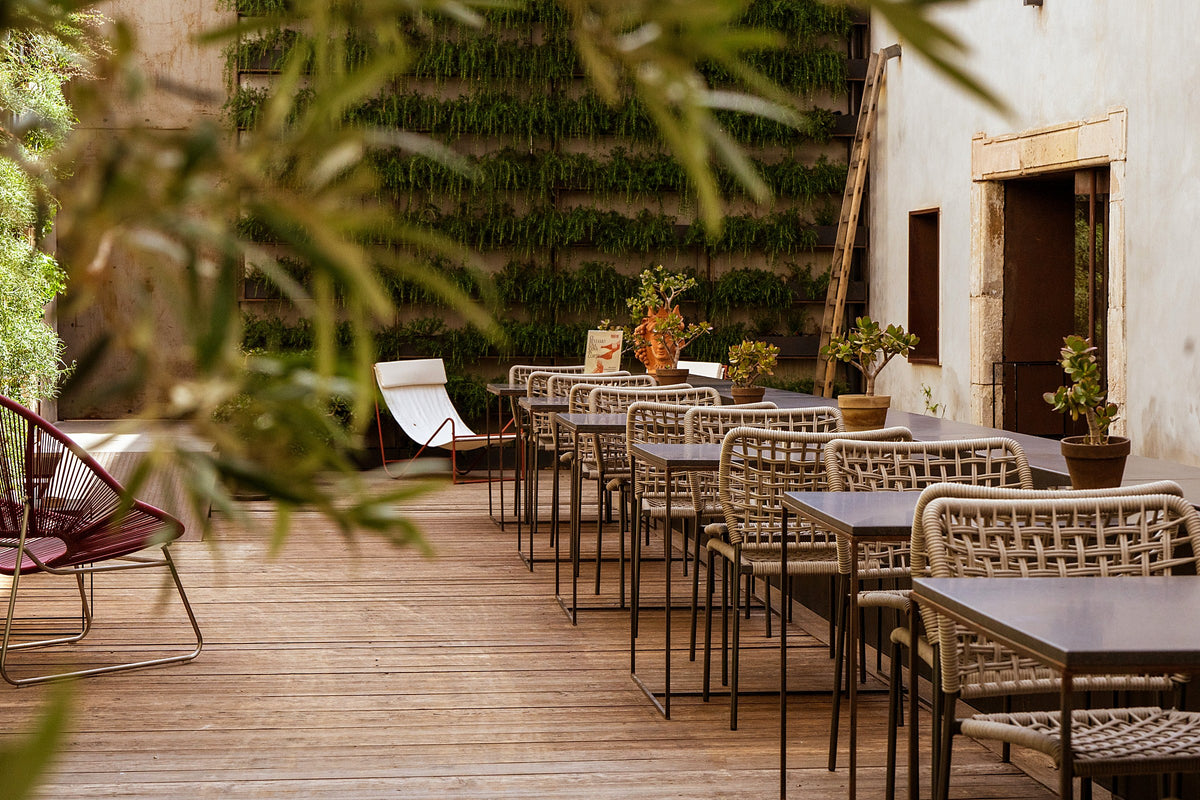 Courtyard terrace with a living green wall and outdoor tables at Habitat Boutique Hotel