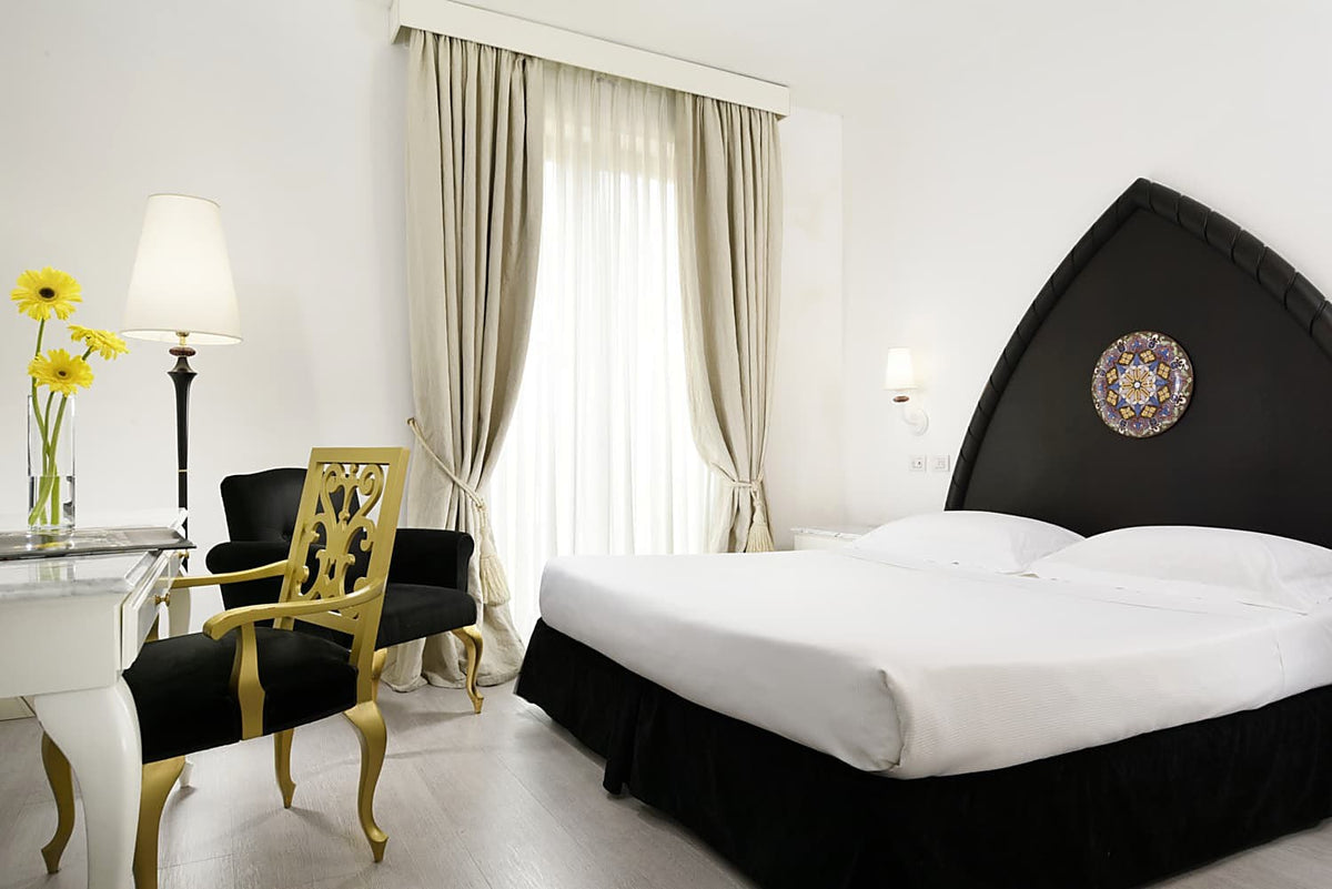 Superior Room with an arched black headboard and Sicilian majolica detail at Palace Catania