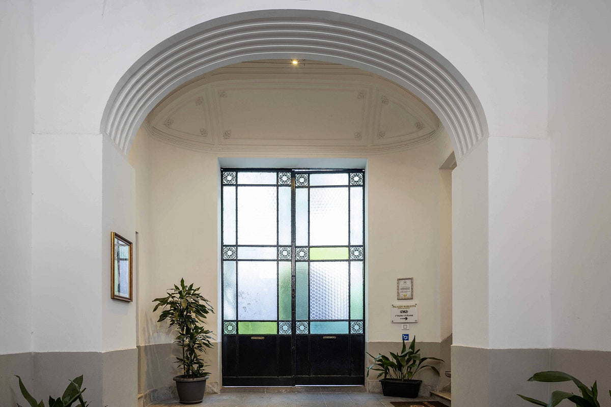 Entrance hall with an arched ceiling and a Liberty-style glazed door at Palazzo Marletta