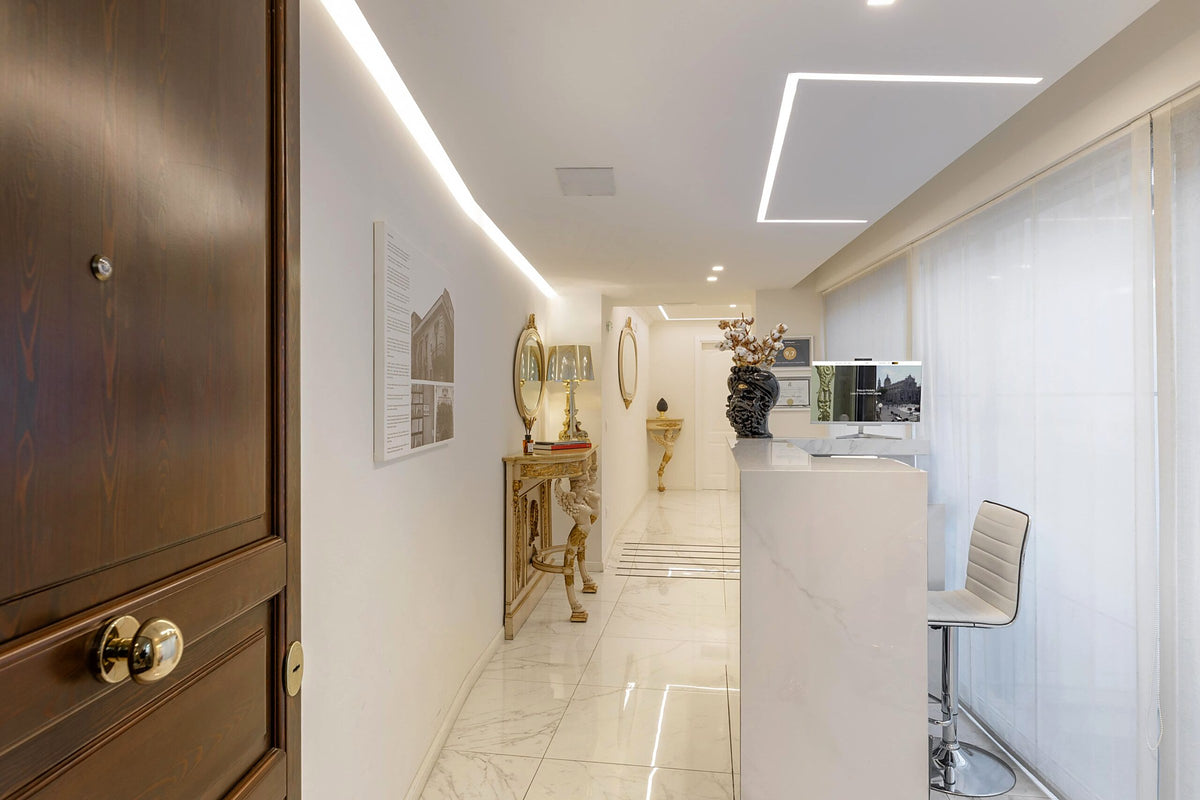 Bright reception corridor with marble floor and an antique gilded console at Palazzo Marletta