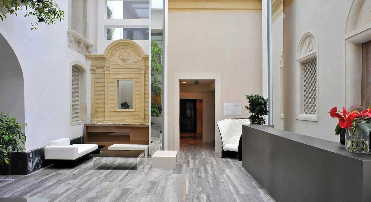 Reception and lounge in a glass-roofed courtyard with Baroque stonework at Romano House
