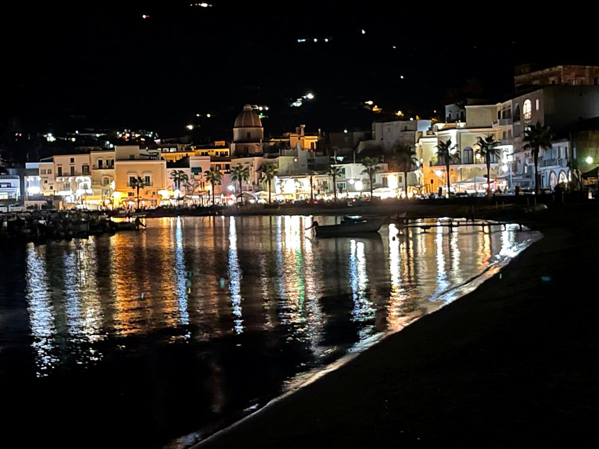 An Ischia seafront village reflected in the bay at night