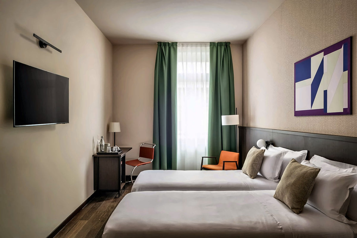Twin room at BYPILLOW Grand Central with green curtains and a wall TV