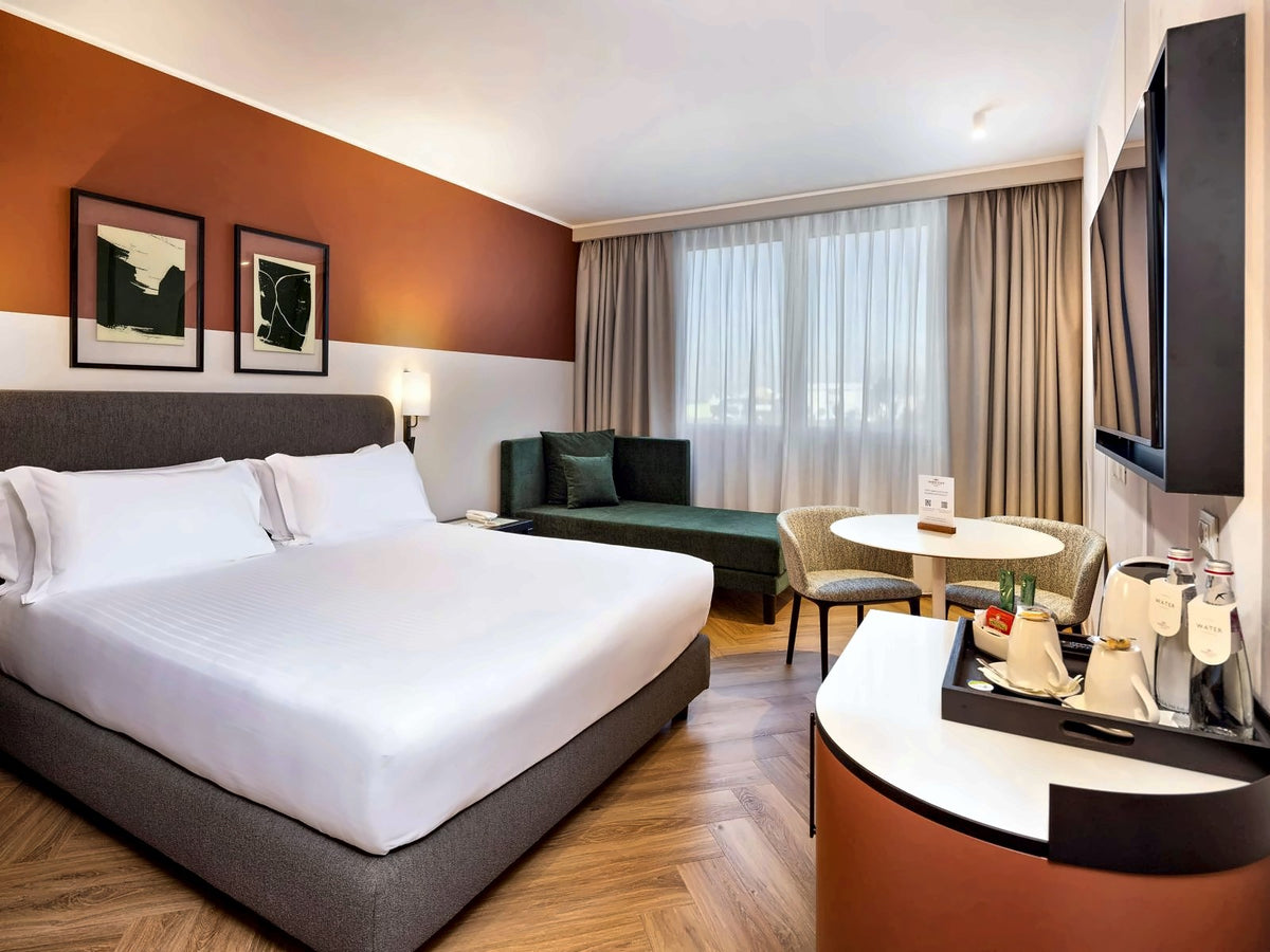 Guest room at Crowne Plaza Padova with a king bed, armchair and round table