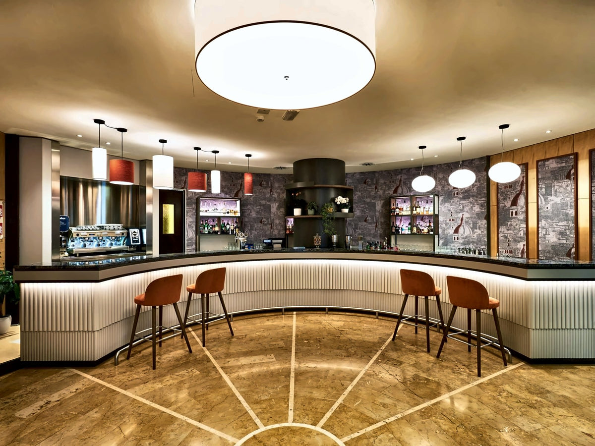 Bar at Crowne Plaza Padova with a curved counter and orange stools