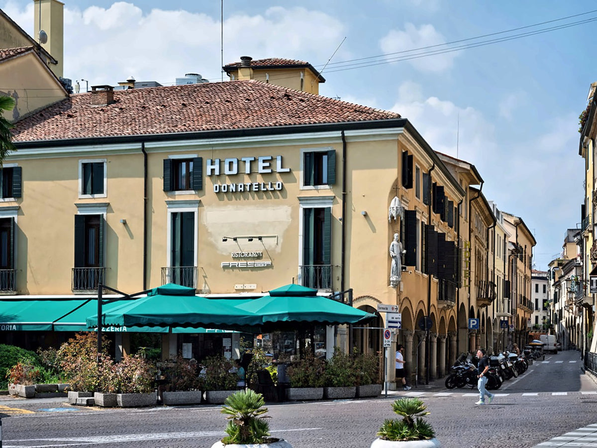 Hotel Donatello facade with green awnings on Via del Santo, Padua