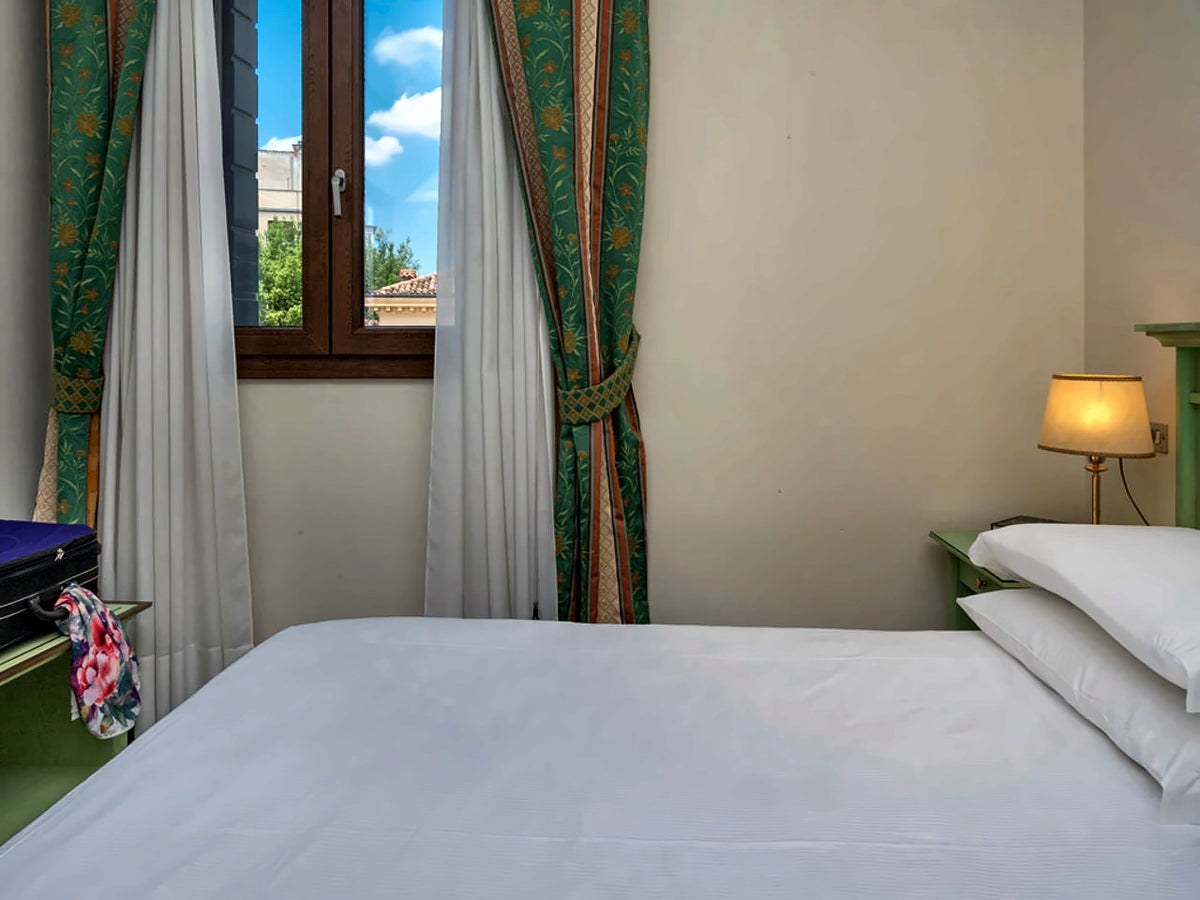 Classic double room at Hotel Donatello with white bedding and a street-facing window