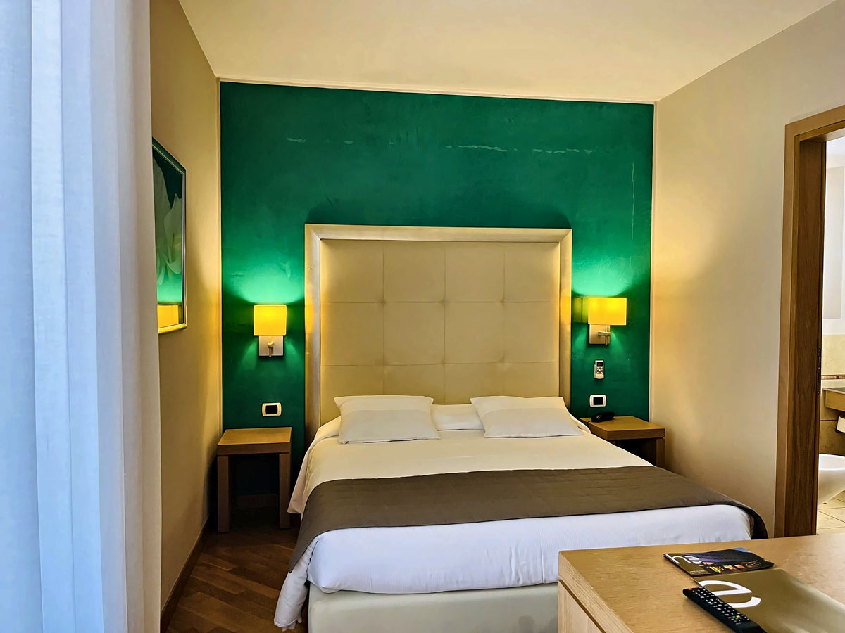 Double room at Hotel Europa with a green feature wall and padded headboard