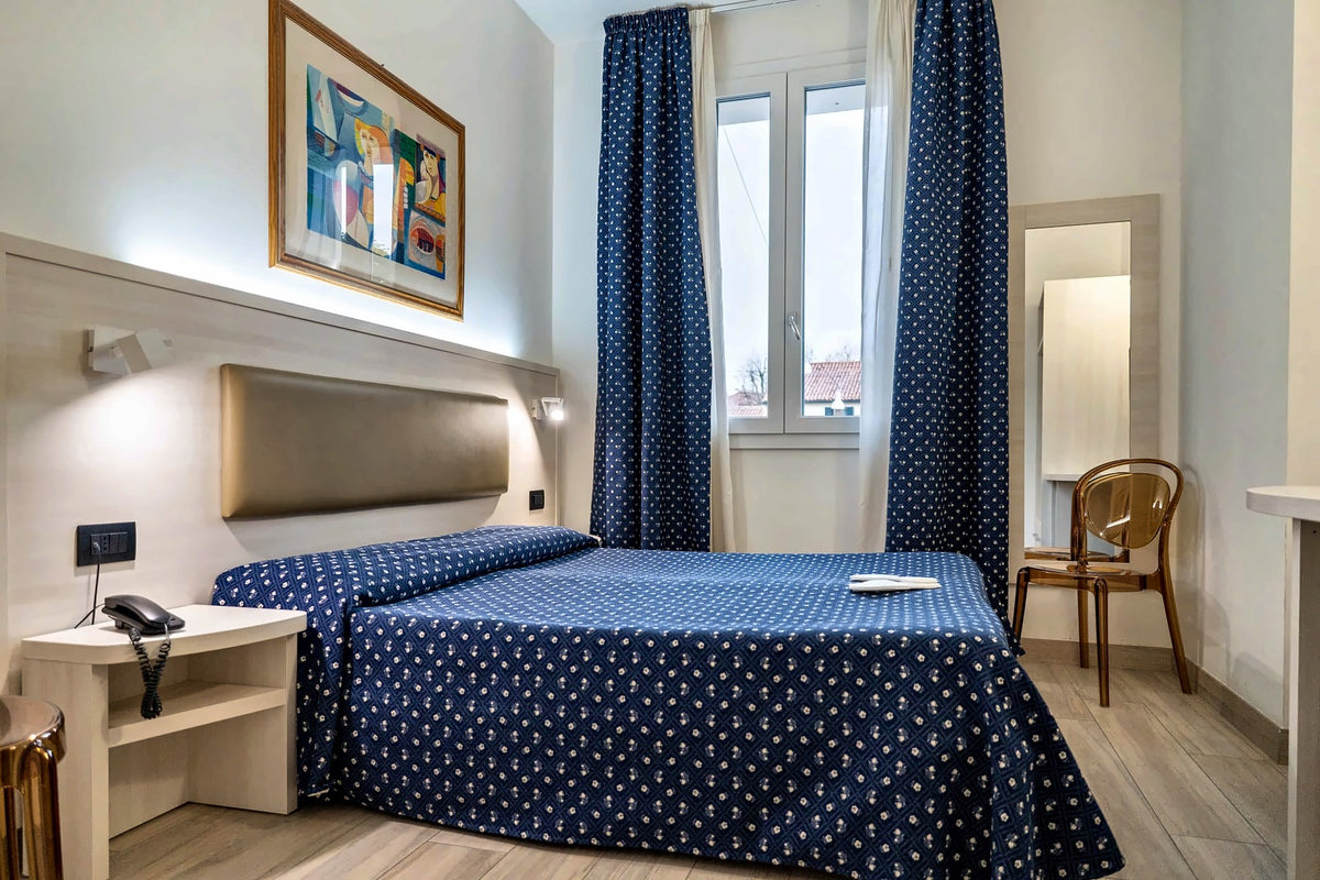 Double room at Hotel Giotto with a blue patterned bedspread and framed print