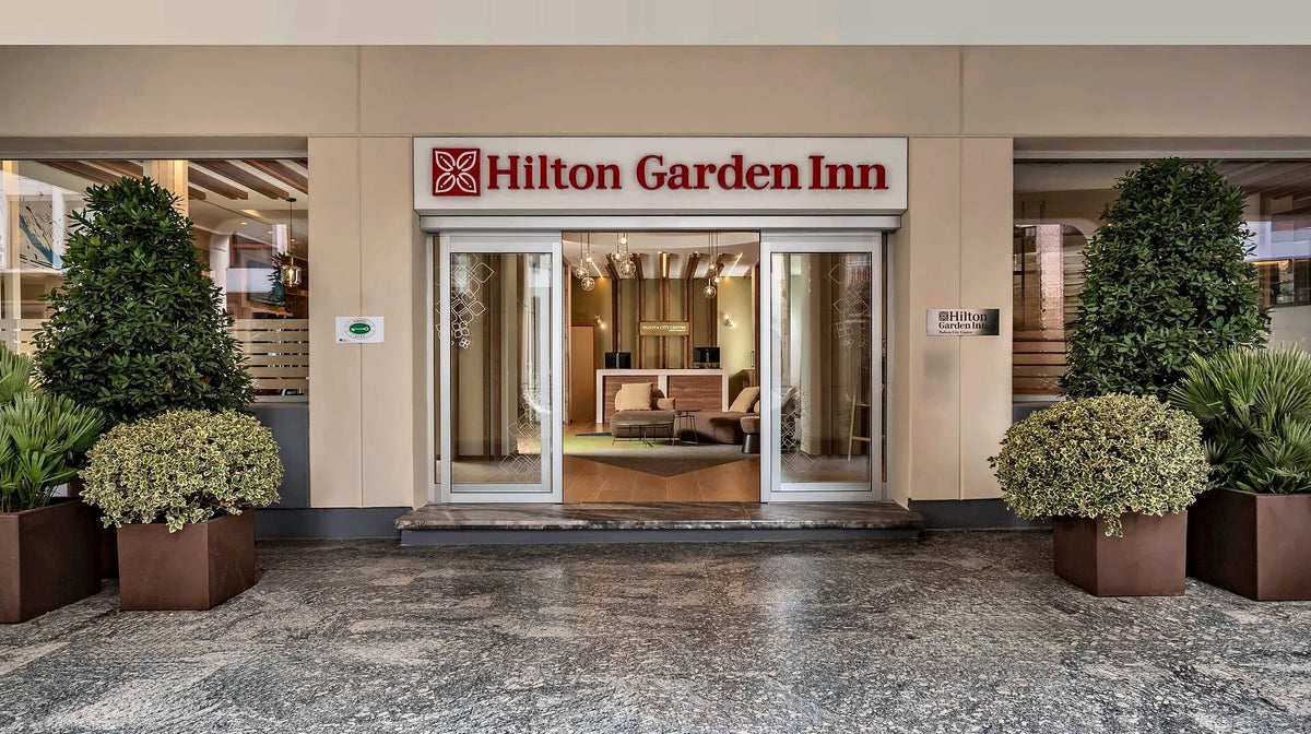 Entrance of Hilton Garden Inn Padova City Centre framed by potted trees
