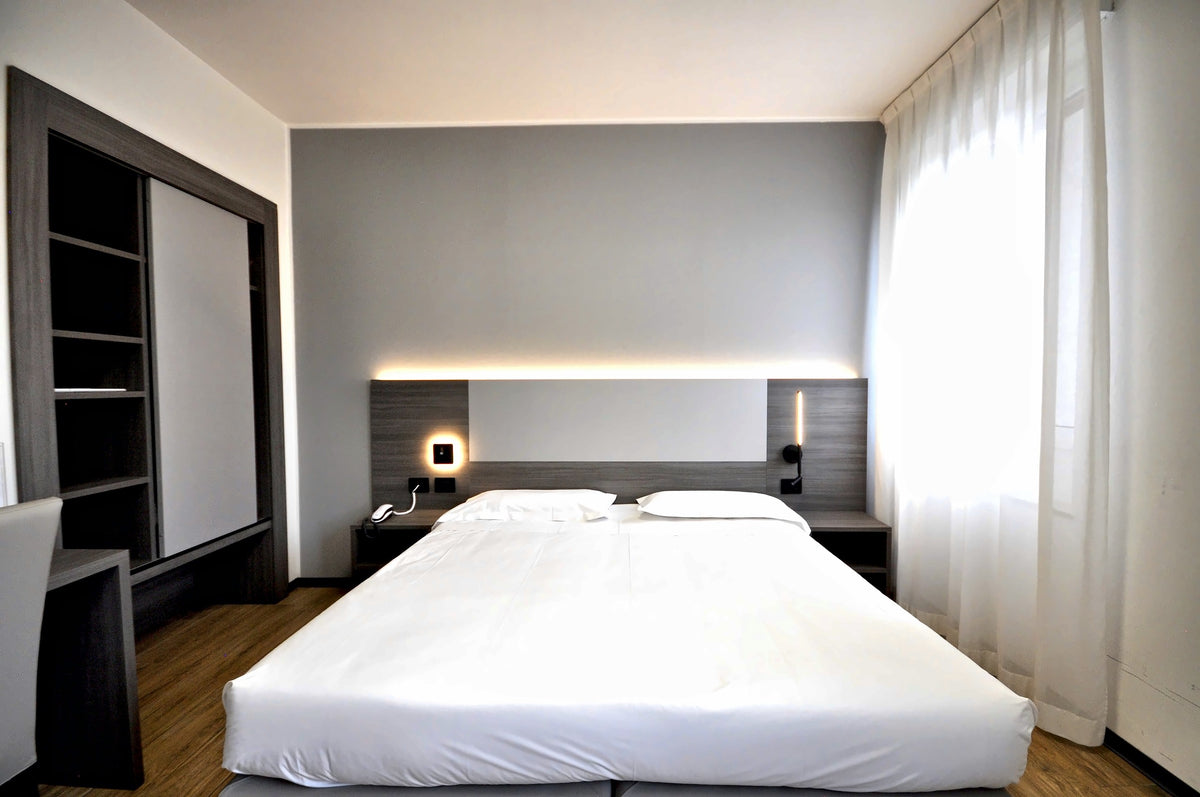 Double room at Hotel Igea with a lit headboard niche and white bedding