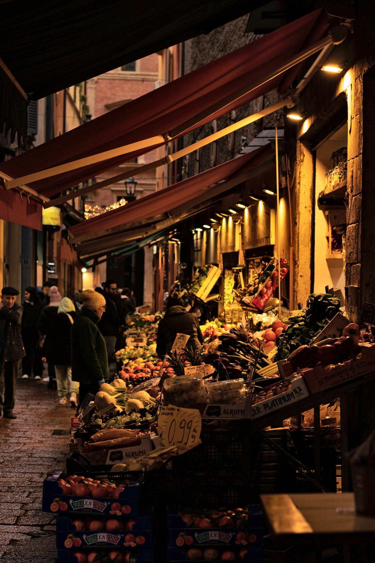 Fruit and vegetable stalls glowing under the arcades at dusk
