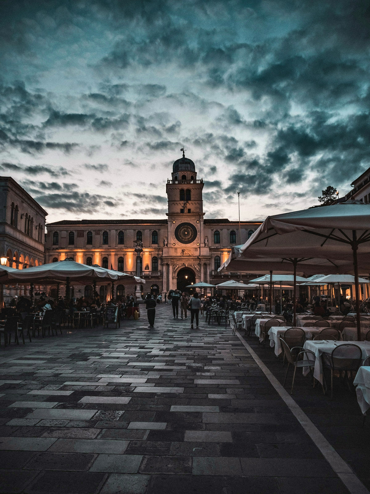 Cafe tables in Piazza dei Signori under an evening sky