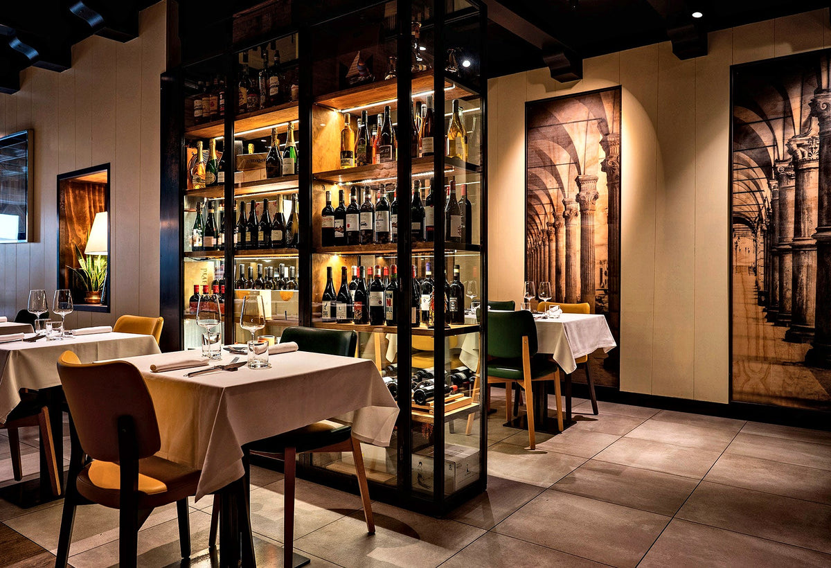 Dining tables beside a glass wine wall at Ai Porteghi Bistrot, Padua