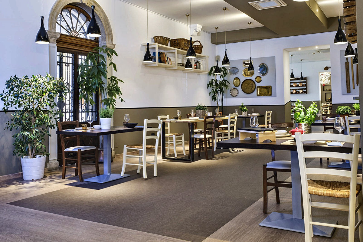 Bright dining room with arched window and plants at Il Desco, Padua