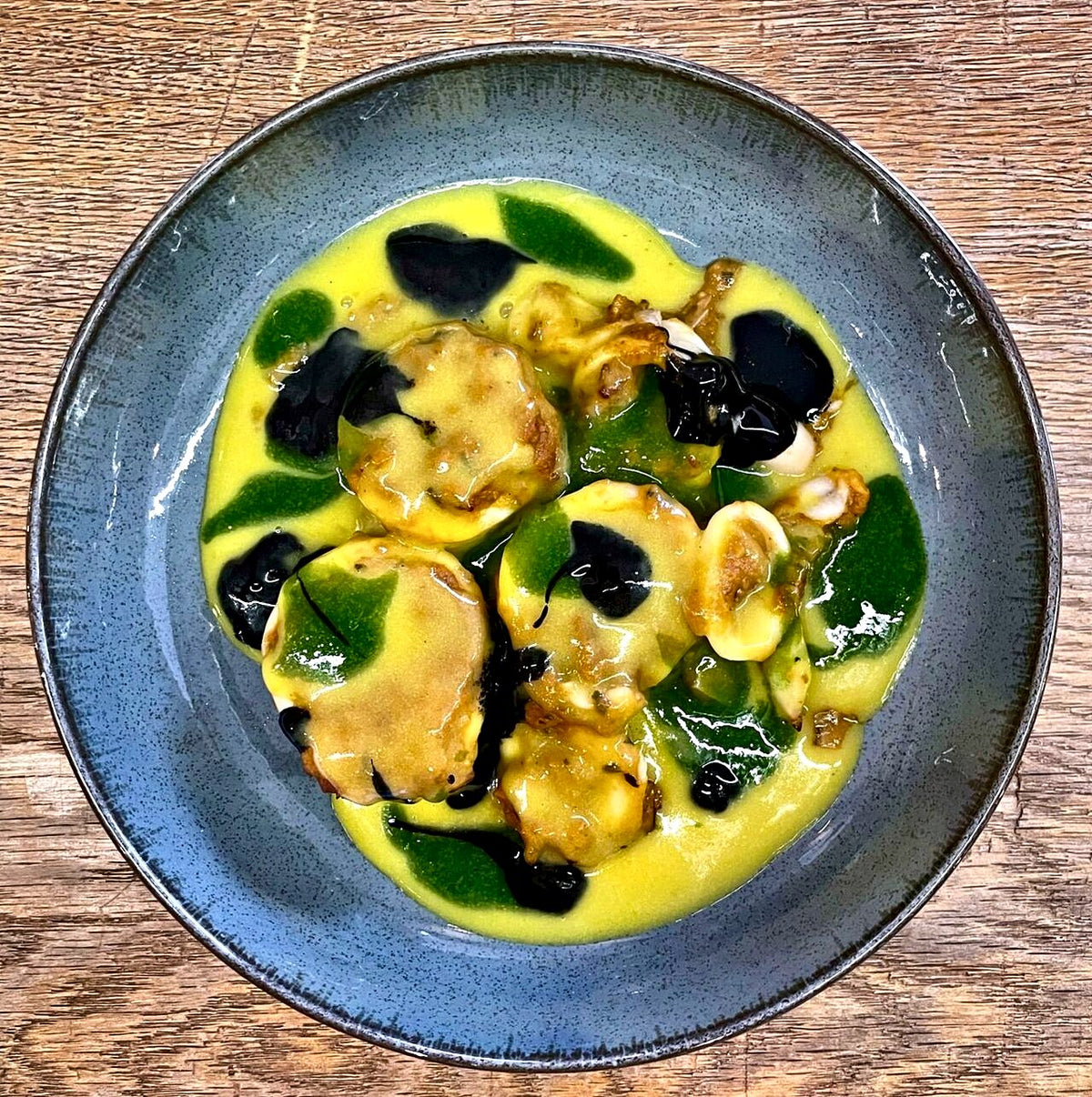 Scallops in saffron cream with squid ink and herb oil at Osteria Le Cave, Padua