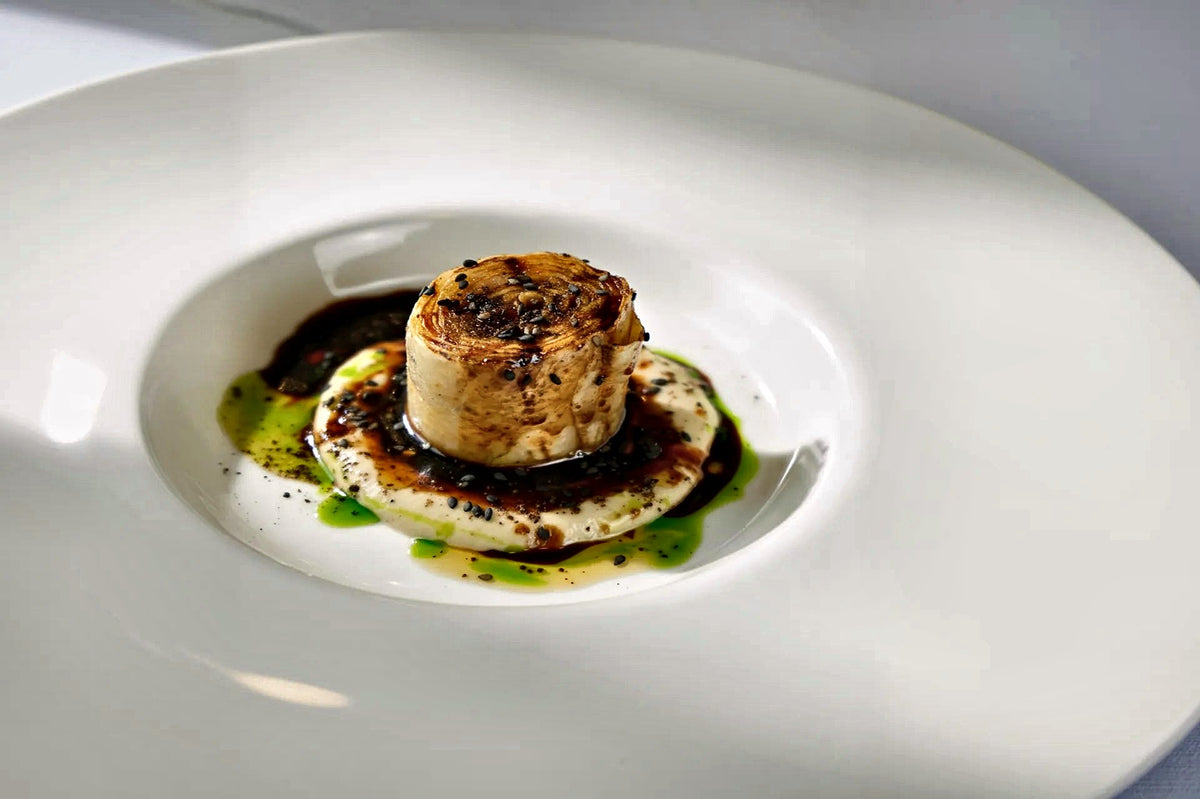 Charcoal-grilled dish with herb oil on a wide white plate at Stefano Mocellin al Padovanino, Padua