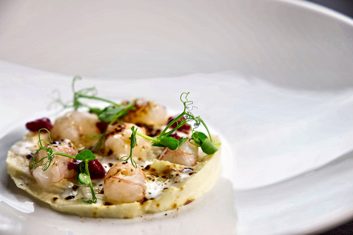 Prawns with pea shoots on a white plate at Osteria Sucabaruca, Padua