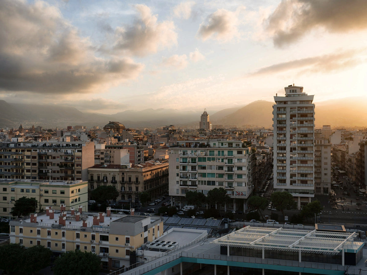 The rooftops of Palermo glowing at sunset under a dramatic sky