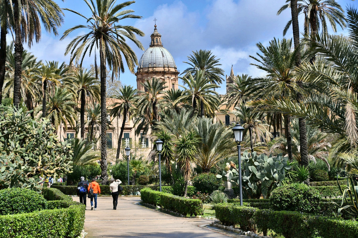 Palms and paths of a garden below a dome in central Palermo