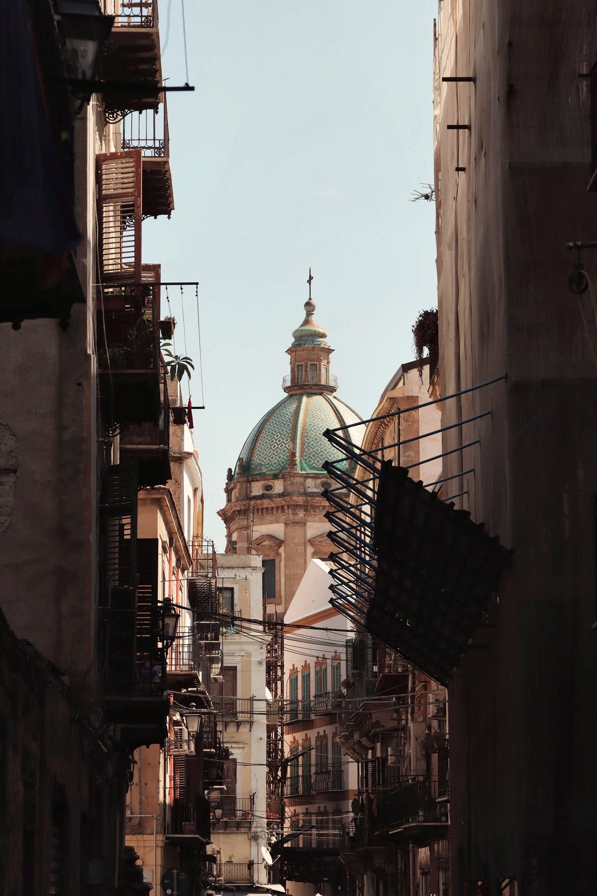 A narrow lane of balconies opening onto a sunlit dome