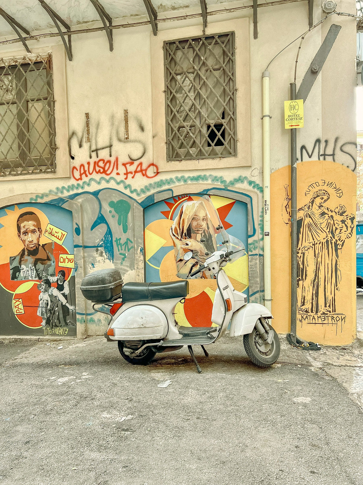 A Vespa parked in front of street art in the old town