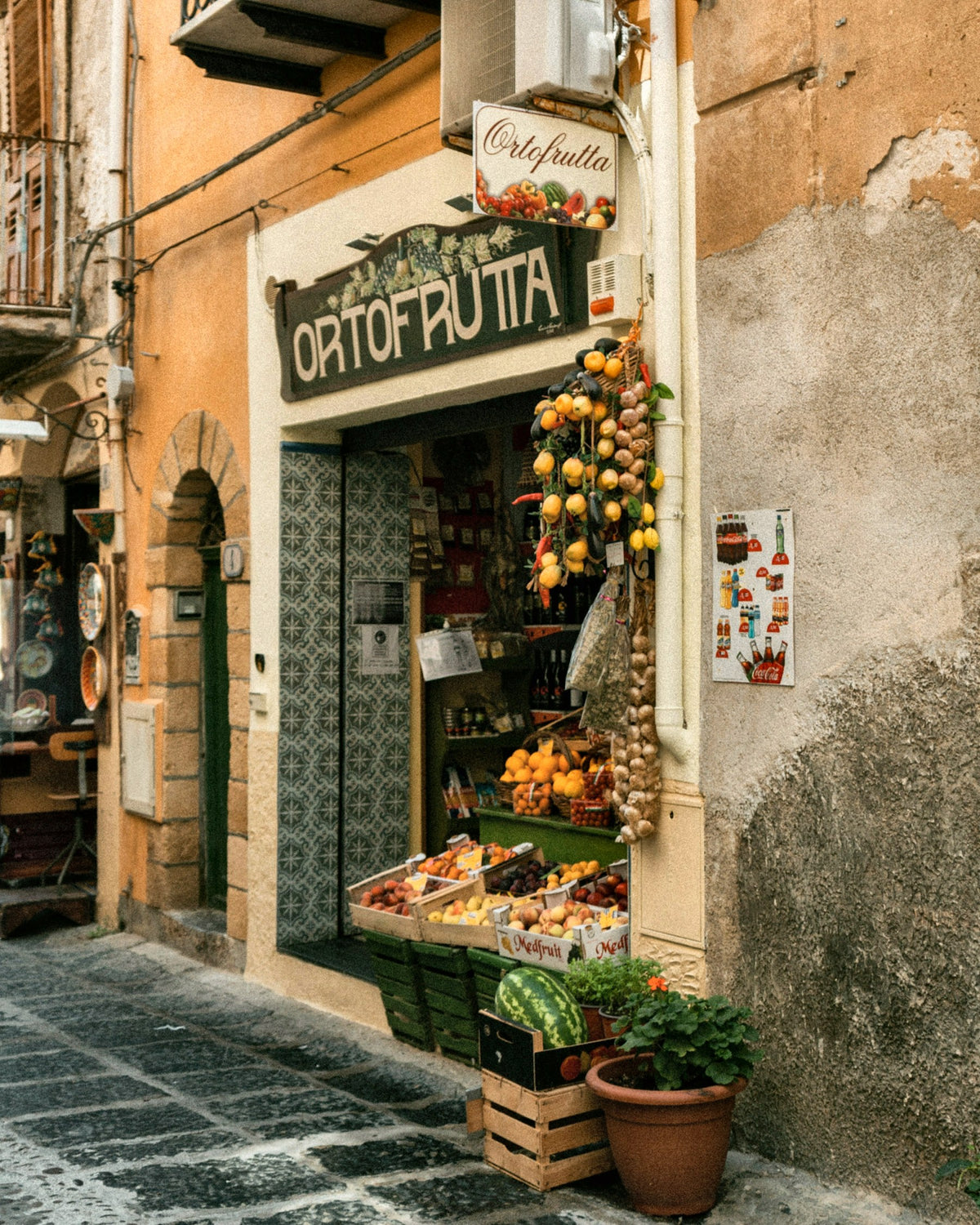 A small fruit and vegetable shop with garlic hung by the door