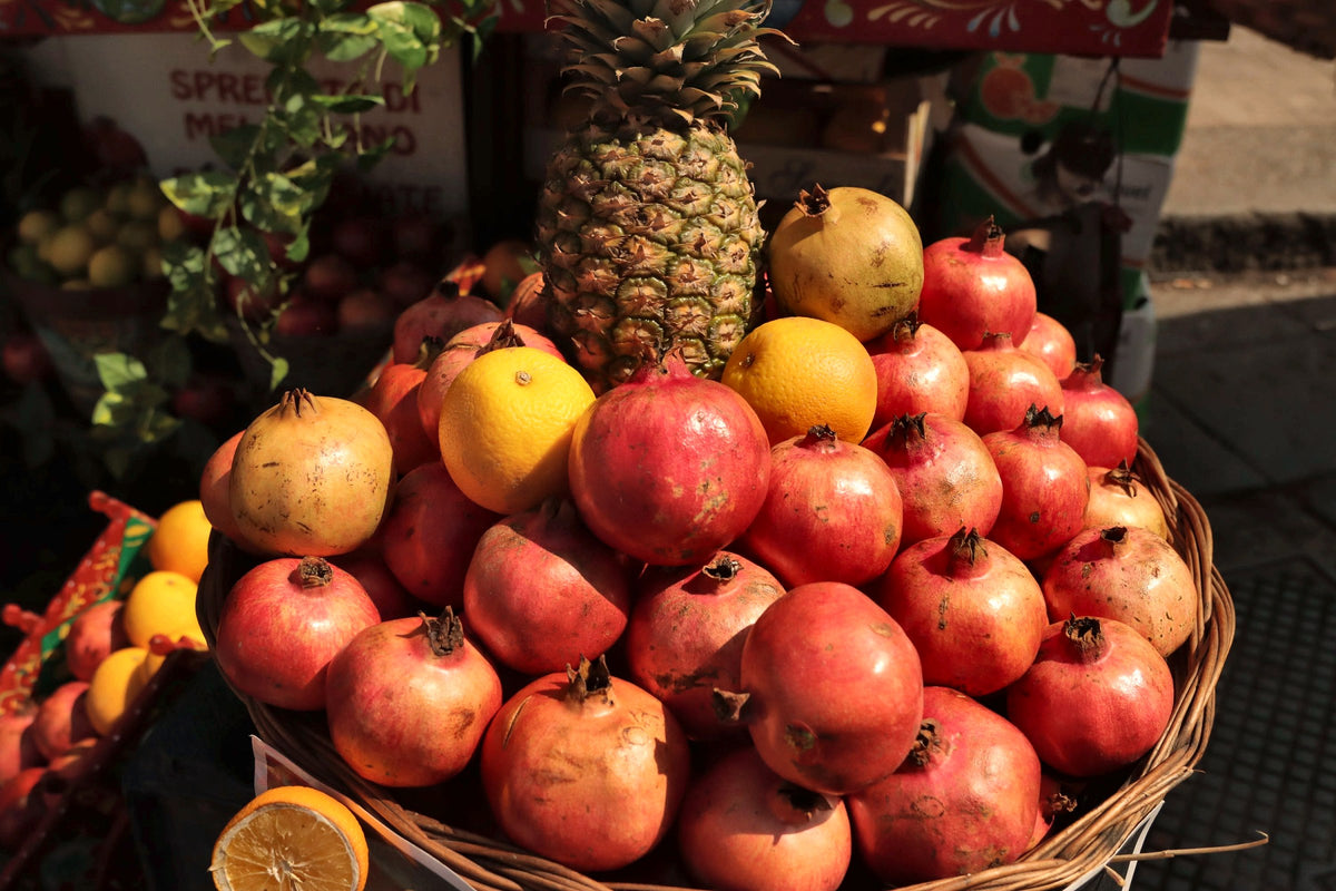 Pomegranates, citrus and a pineapple on a market stall