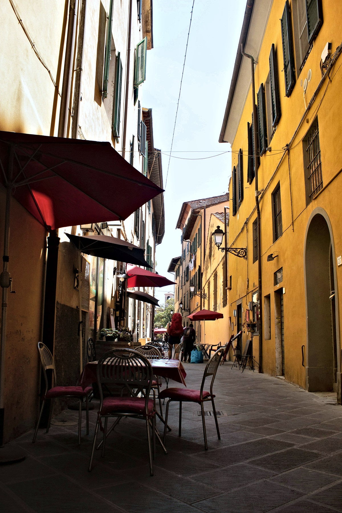 Cafe tables and red awnings in a narrow street of the centre