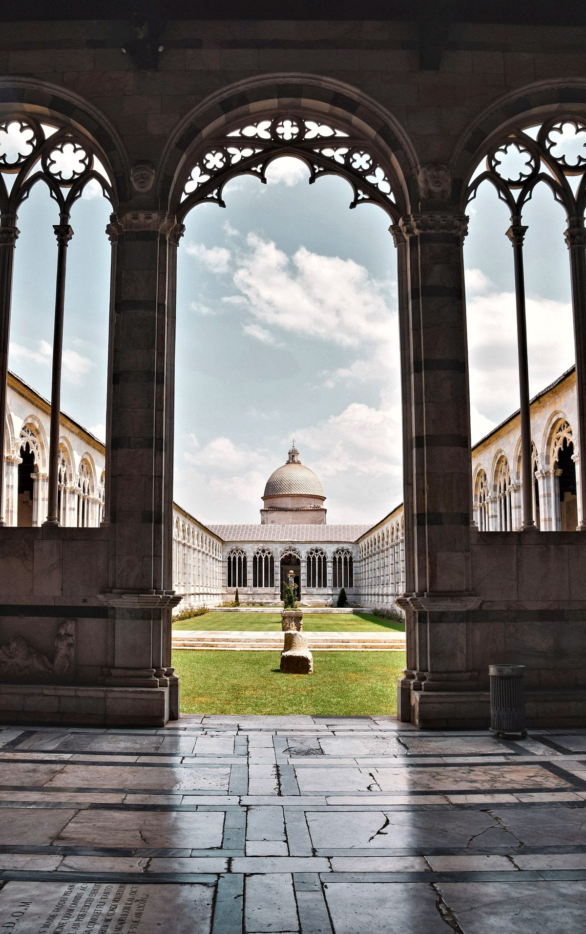 Gothic tracery of the Camposanto cloister framing the cathedral dome